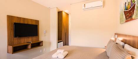 Habitación de hotel con una cama grande, televisor montado, armario y equipo de aire acondicionado.