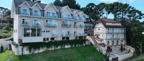 A multi-story hotel with balconies, a sloped roof, and a grassy area in front.