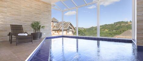 A spa area with a large indoor pool, a wicker chair, and a potted plant.