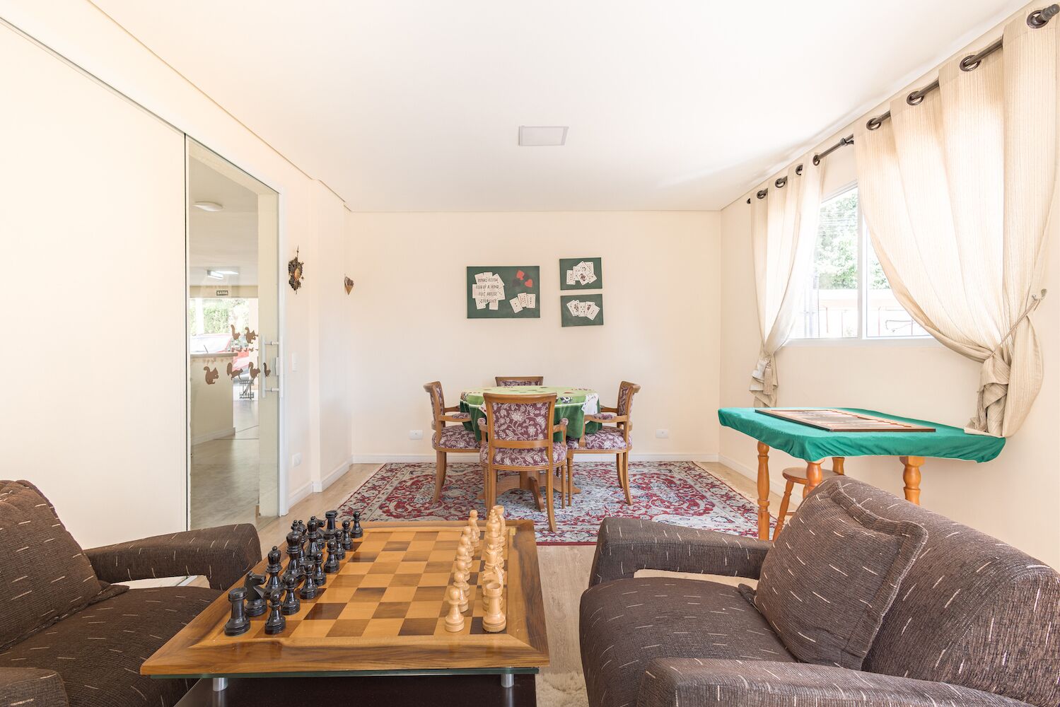 Een woonkamer met een schaakbord, een bank, een eettafel met stoelen en een pooltafel.