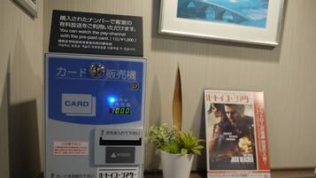 A card reader with a digital display, a potted plant, and a movie poster on a table.