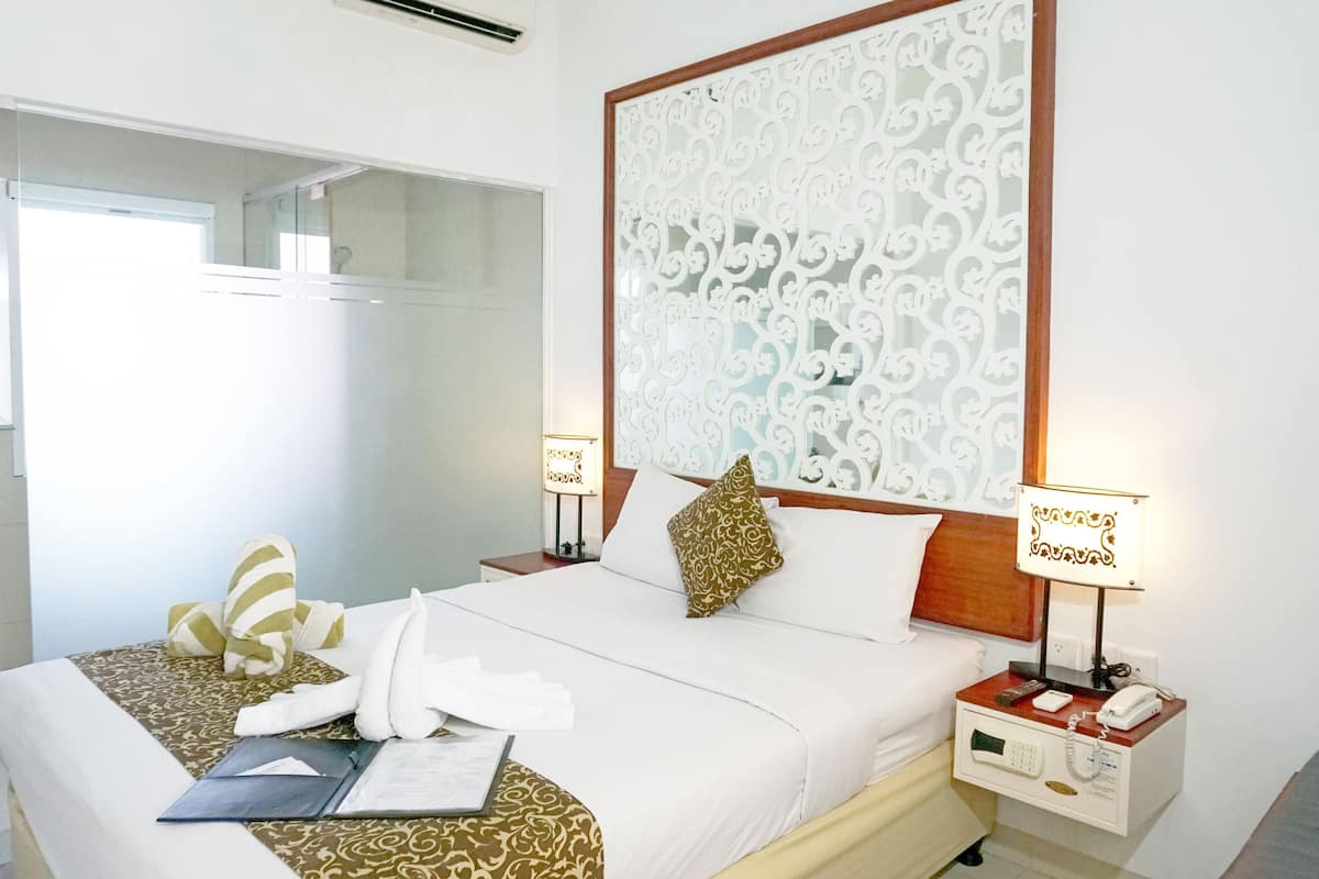 A hotel room with a large bed, two bedside tables with lamps, a bedside phone, and a mirror.