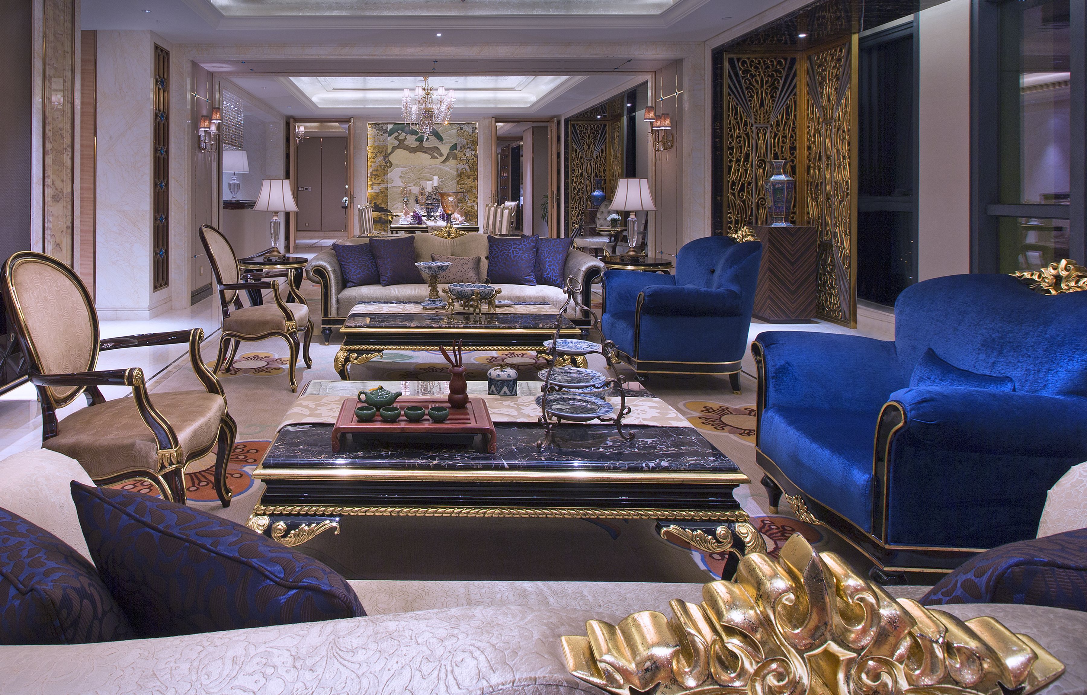 A luxurious living room with a grand chandelier, plush seating, and ornate decor.