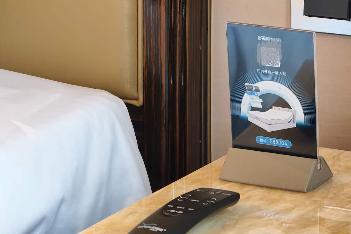 Une chambre d’hôtel équipée d’un lit, d’une télécommande et d’un présentoir promotionnel pour un matelas.