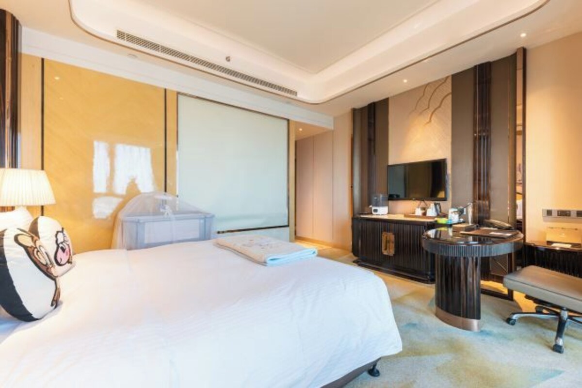 Een moderne hotelkamer met een groot bed, een nachtkastje, een bureau en een spiegel.
