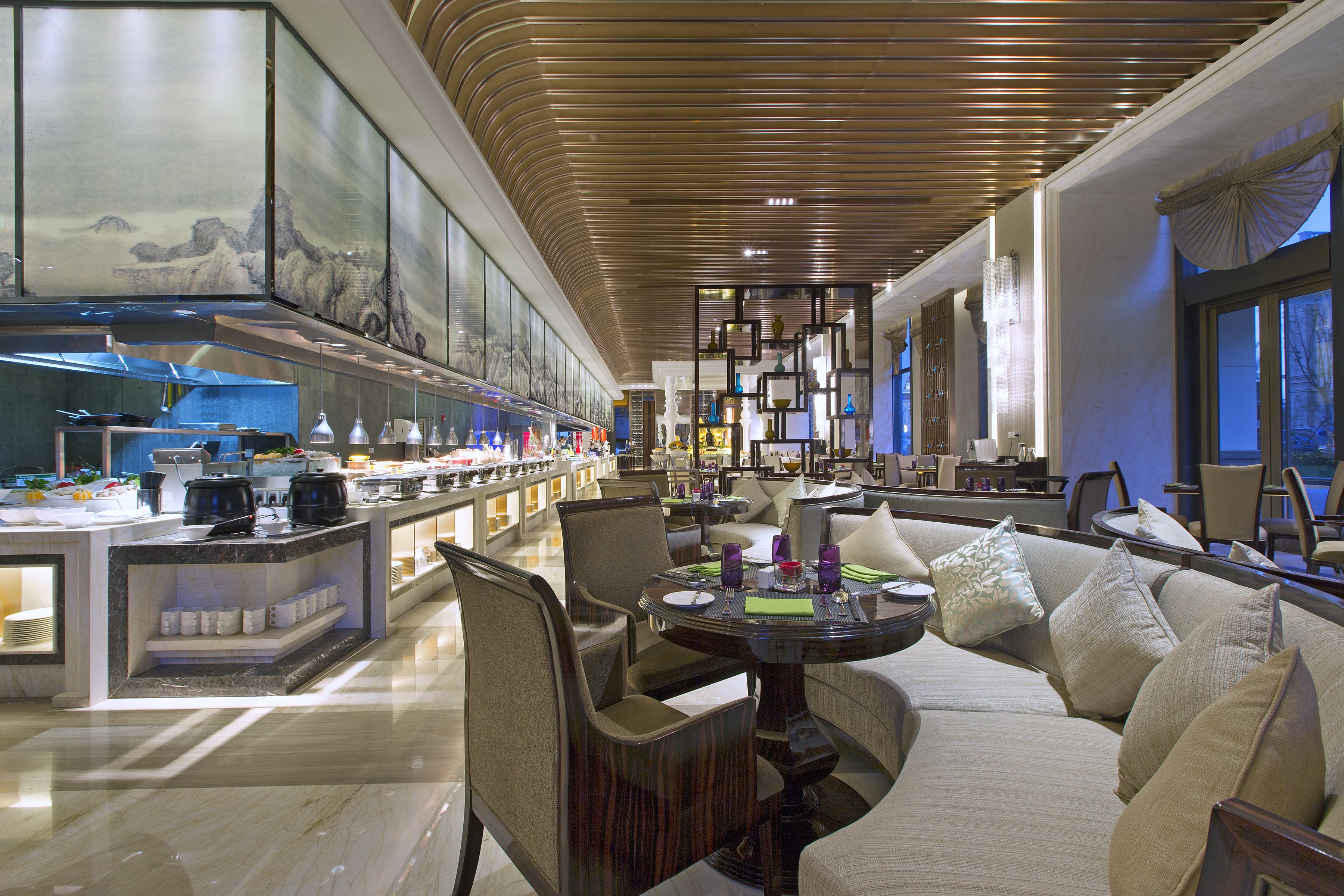 Um amplo hall de hotel com design moderno, apresentando uma área de estar com sofá e cadeiras, um bar com balcão e uma parede grande com obras de arte.