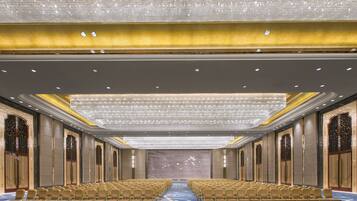 A large conference room with rows of chairs, a patterned carpet, and a chandelier.