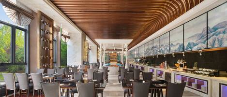 A spacious restaurant with high ceilings and a modern design, featuring multiple dining tables and chairs.