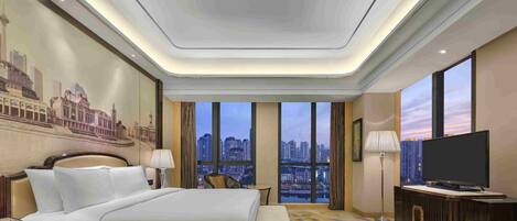 Una habitación de hotel moderna con una cama grande, un escritorio, un televisor y vista a la ciudad.