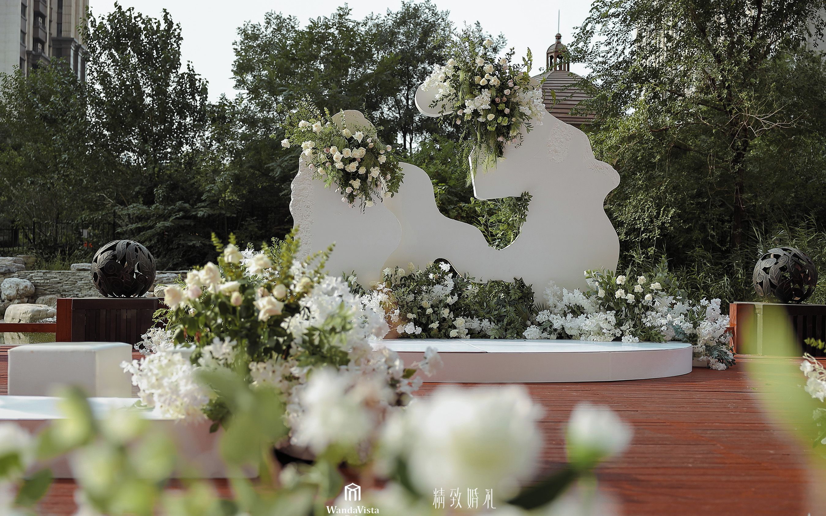 Une décoration de mariage comprenant une composition florale blanche et une grande sculpture blanche.