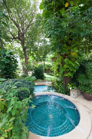 Una piscina circular rodeada de abundante vegetación y árboles.