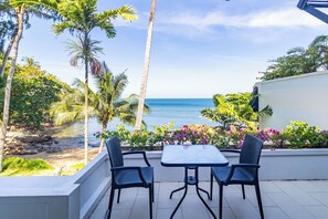 Un patio con mesa y sillas con vista a una playa y al océano.