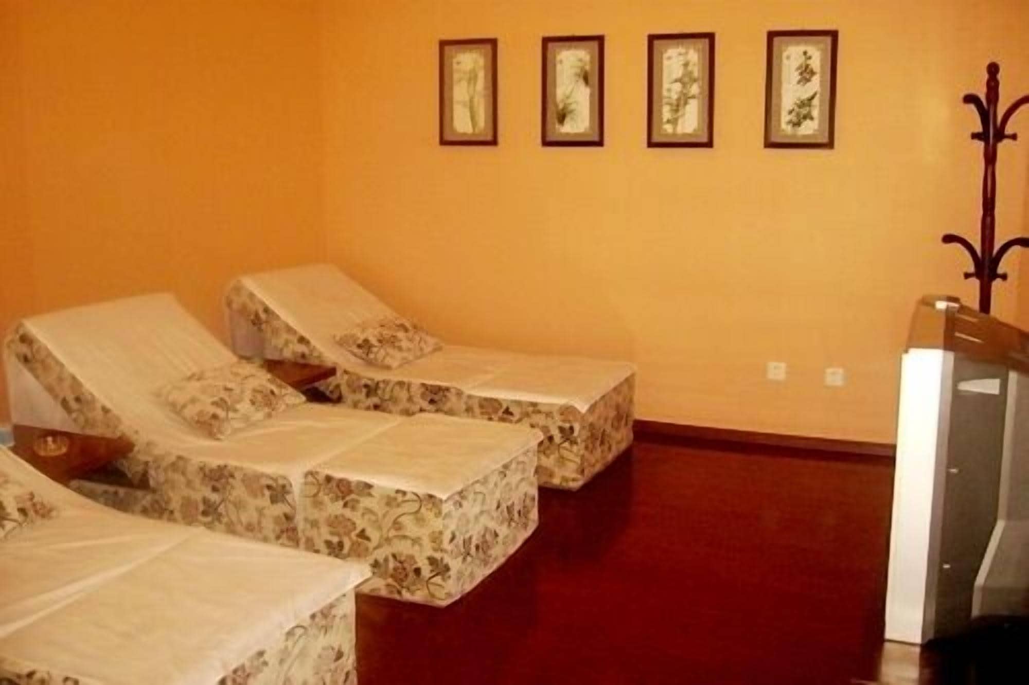 Una habitación con tres camas cubiertas con ropa de cama estampada con motivos florales, suelo de madera y una pared con cuatro cuadros enmarcados.