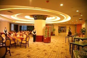 A spacious banquet hall with round tables and chairs, a central pillar, and a reception area. - Gaosu Shenzhou Hotel (Xi'an)