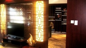 Een moderne woonkamer met een flatscreen televisie, decoratieve wandpanelen en een houten vloer.