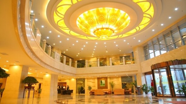 Een ruime lobby met een centraal, rond plafondontwerp, meerdere verdiepingen en een receptie.