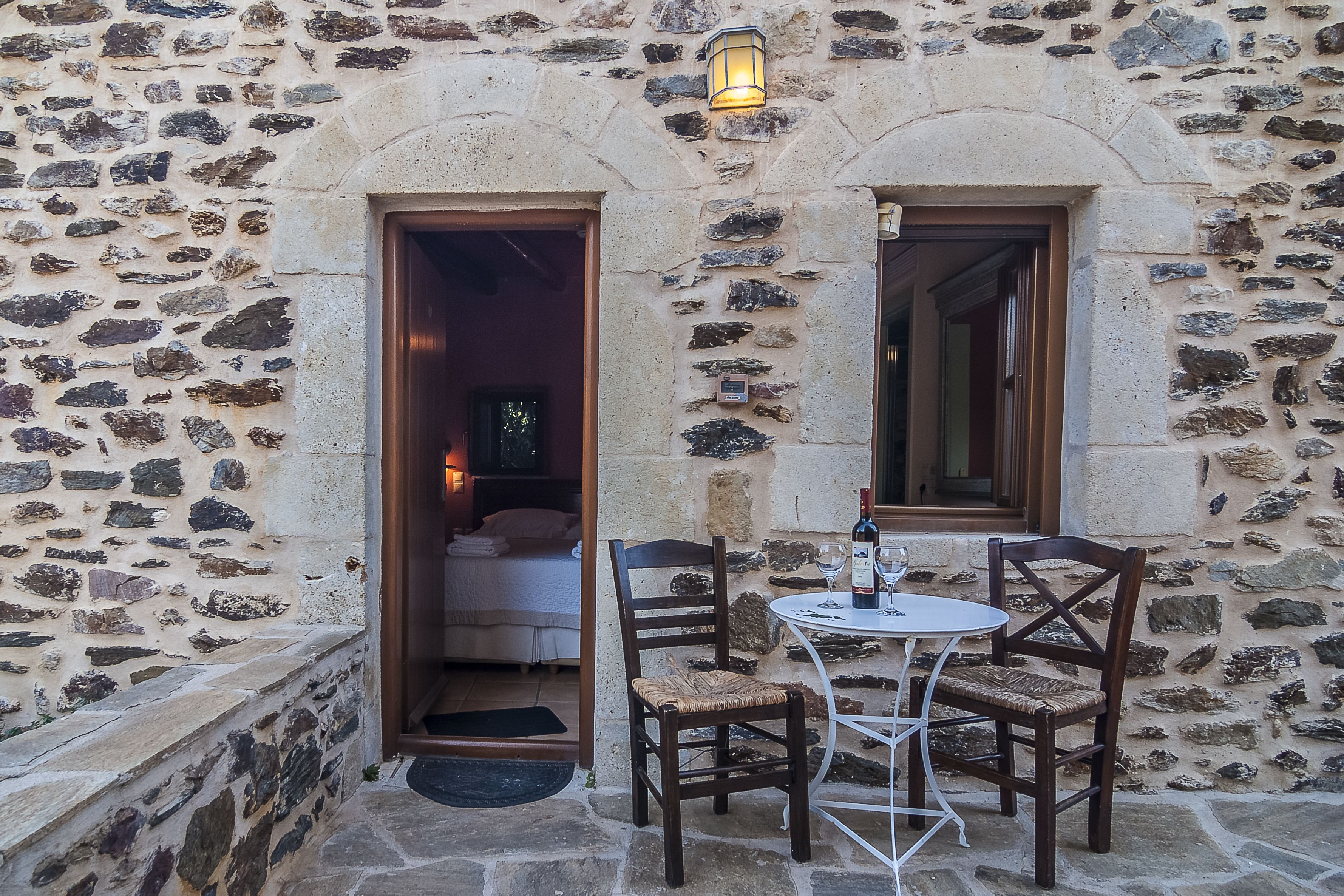 A stone building with a small outdoor seating area featuring a table and chairs.