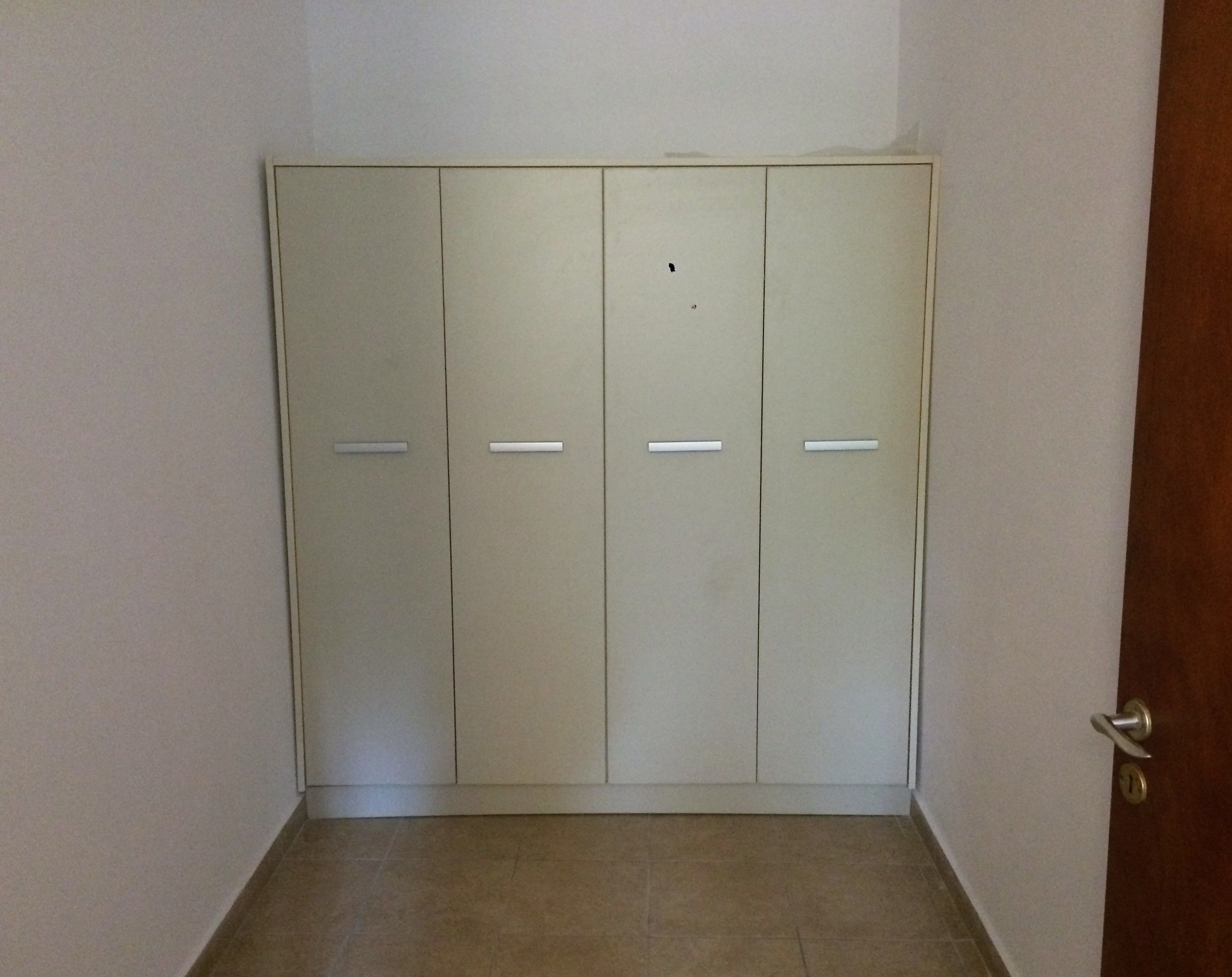 A closed door with a keyhole, a tiled floor, and a plain wall.