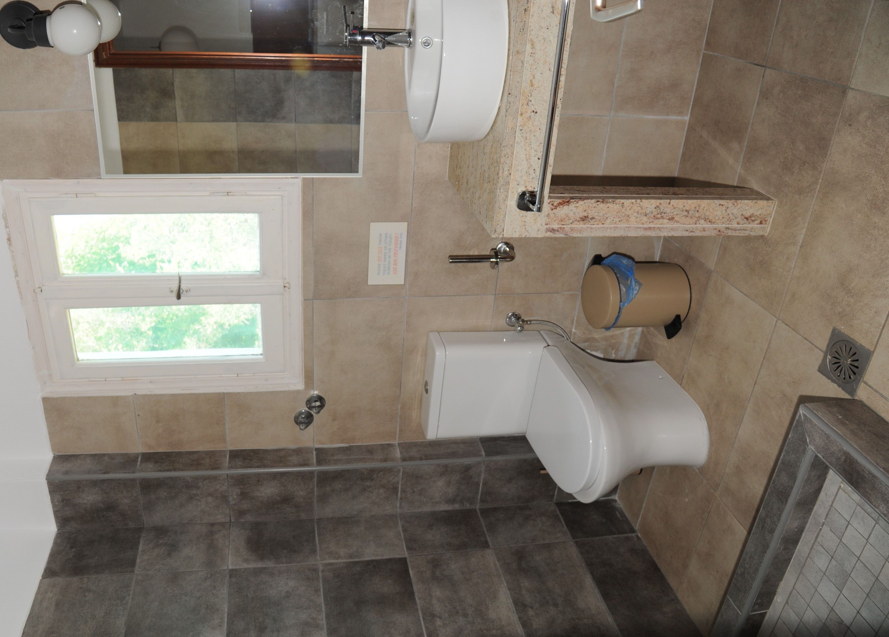 Un baño con inodoro, lavabo y ventana.