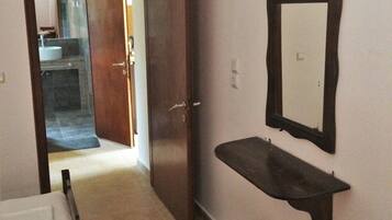 Una habitación de hotel con una cama, una mesita, un espejo y una puerta que da a un baño.