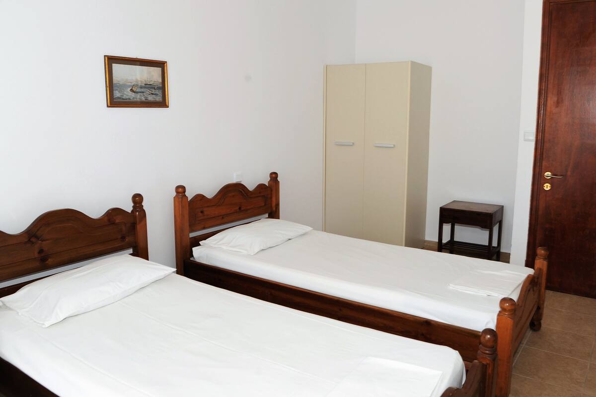 A room with two wooden beds, a wardrobe, and a small table.