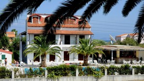 A two-story building with a red-tiled roof, a swimming pool, and outdoor seating.