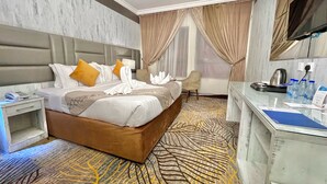 Habitación de hotel con cama, escritorio, silla, televisor y baño.