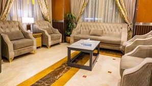 Un hall de hotel con una zona de estar que incluye dos sofás y dos sillones, una mesa de centro y una lámpara.