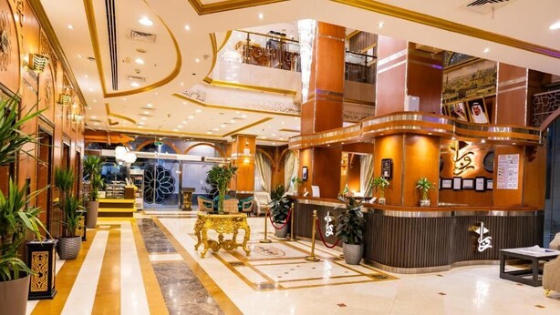 Un hall amplio con una recepción, una escalera y una mesa dorada decorativa.