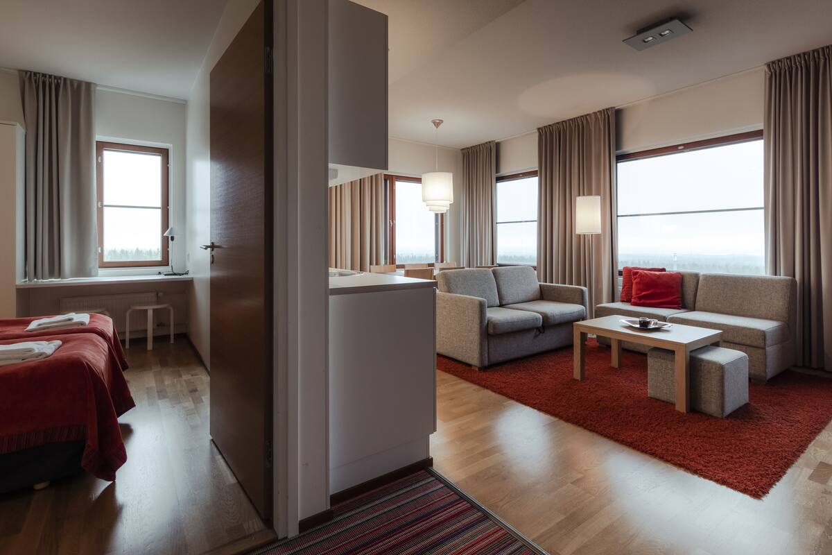 A hotel room with a bed, a desk, a sofa, and a coffee table.