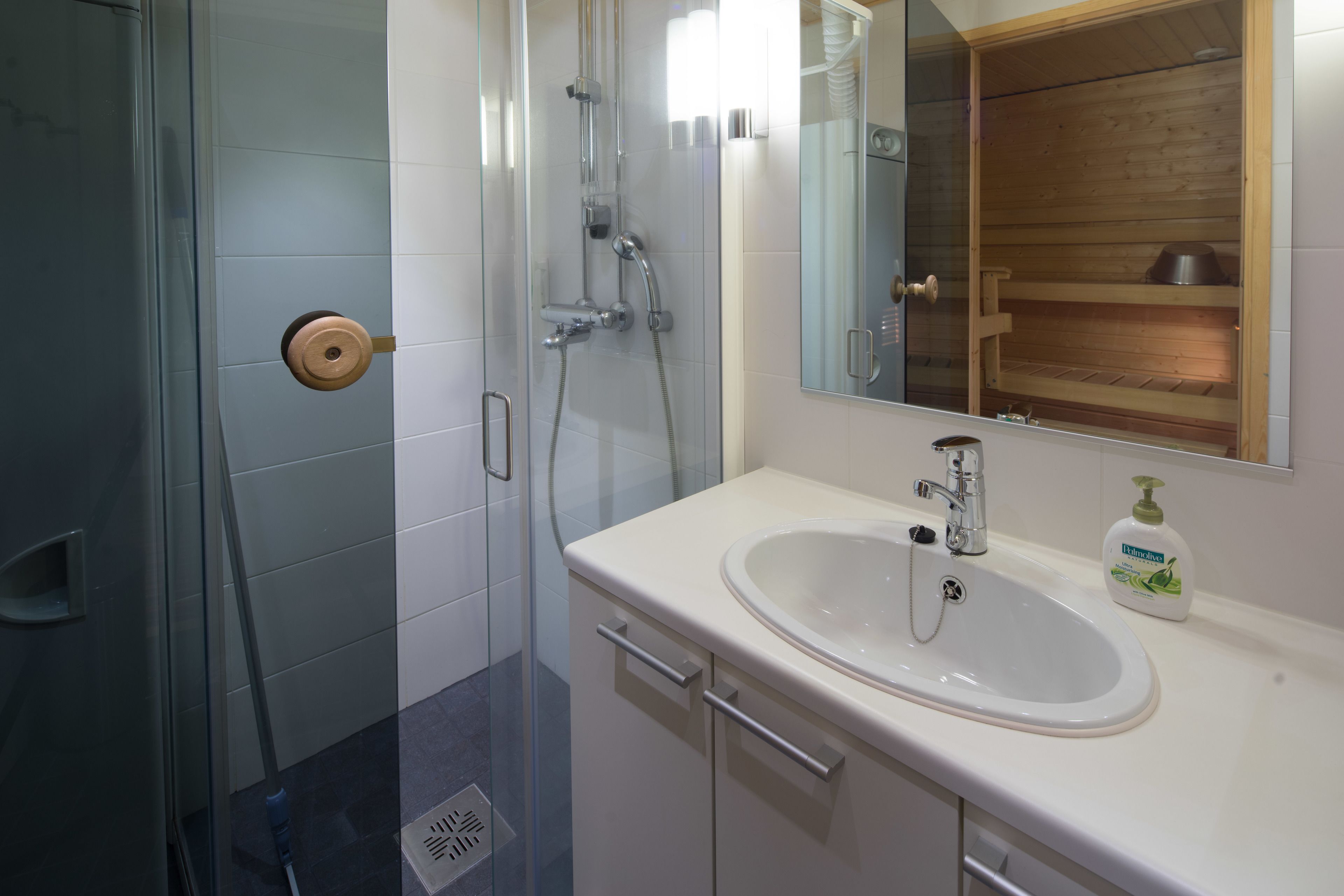Une salle de bain avec une douche à parois de verre, un lavabo blanc et un meuble en bois.