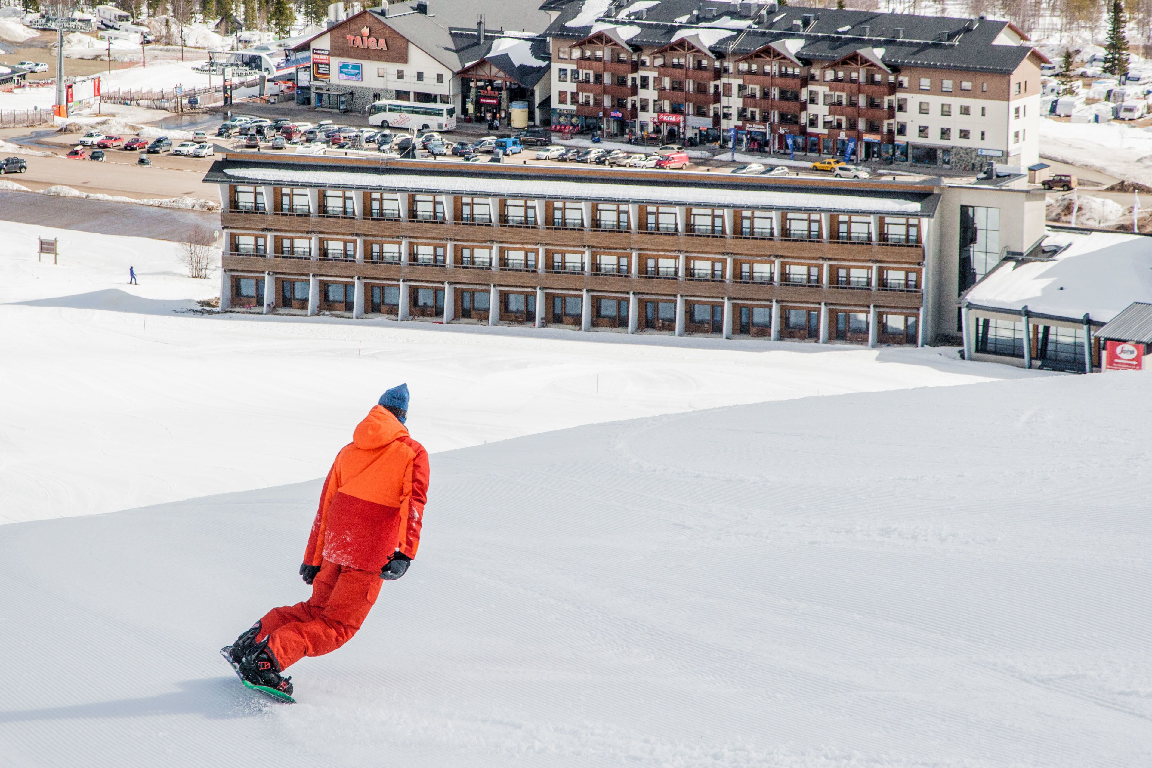 A person snowboarding down a slope with a building in the background.