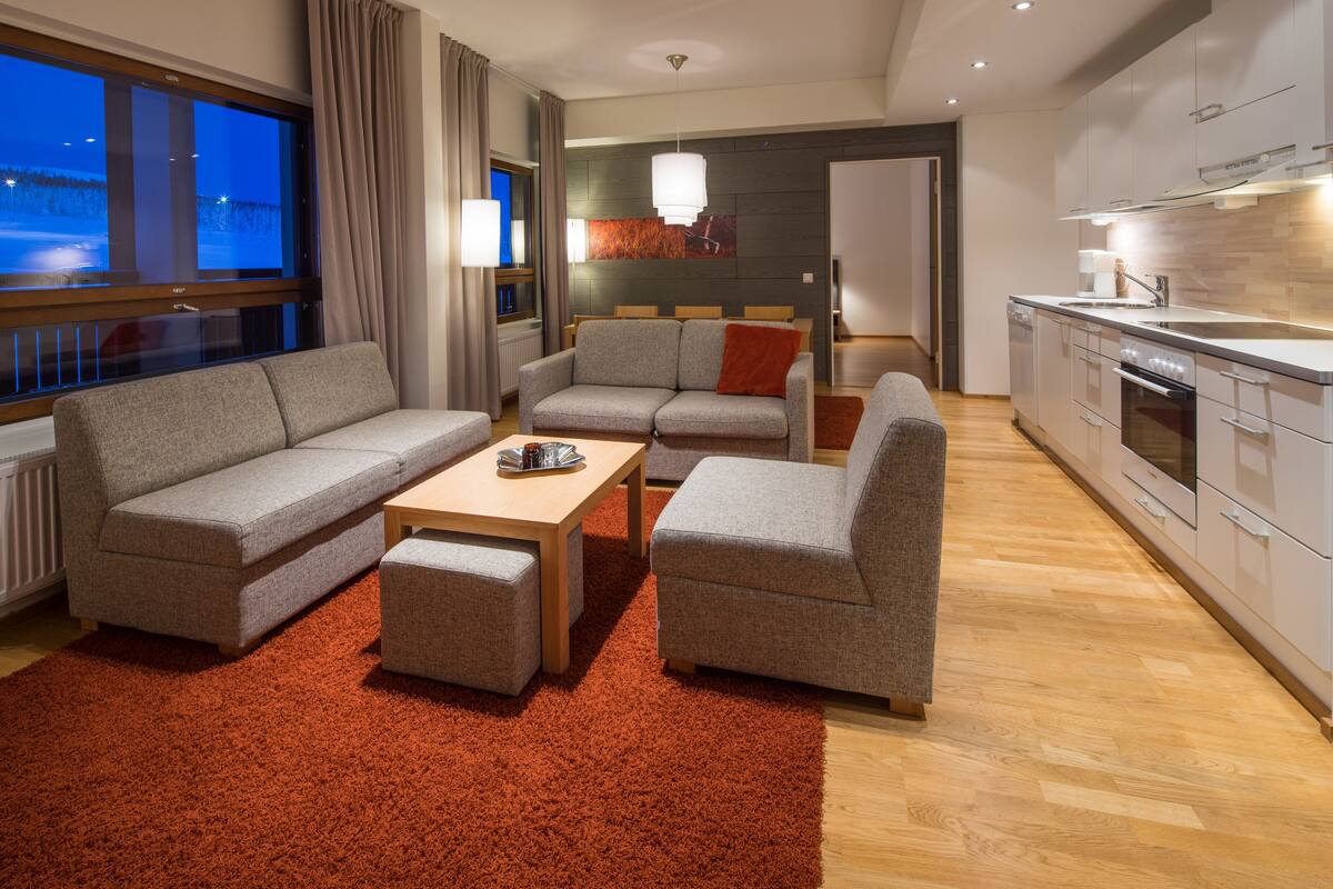 A modern living room with a sofa set, a coffee table, and a red rug.