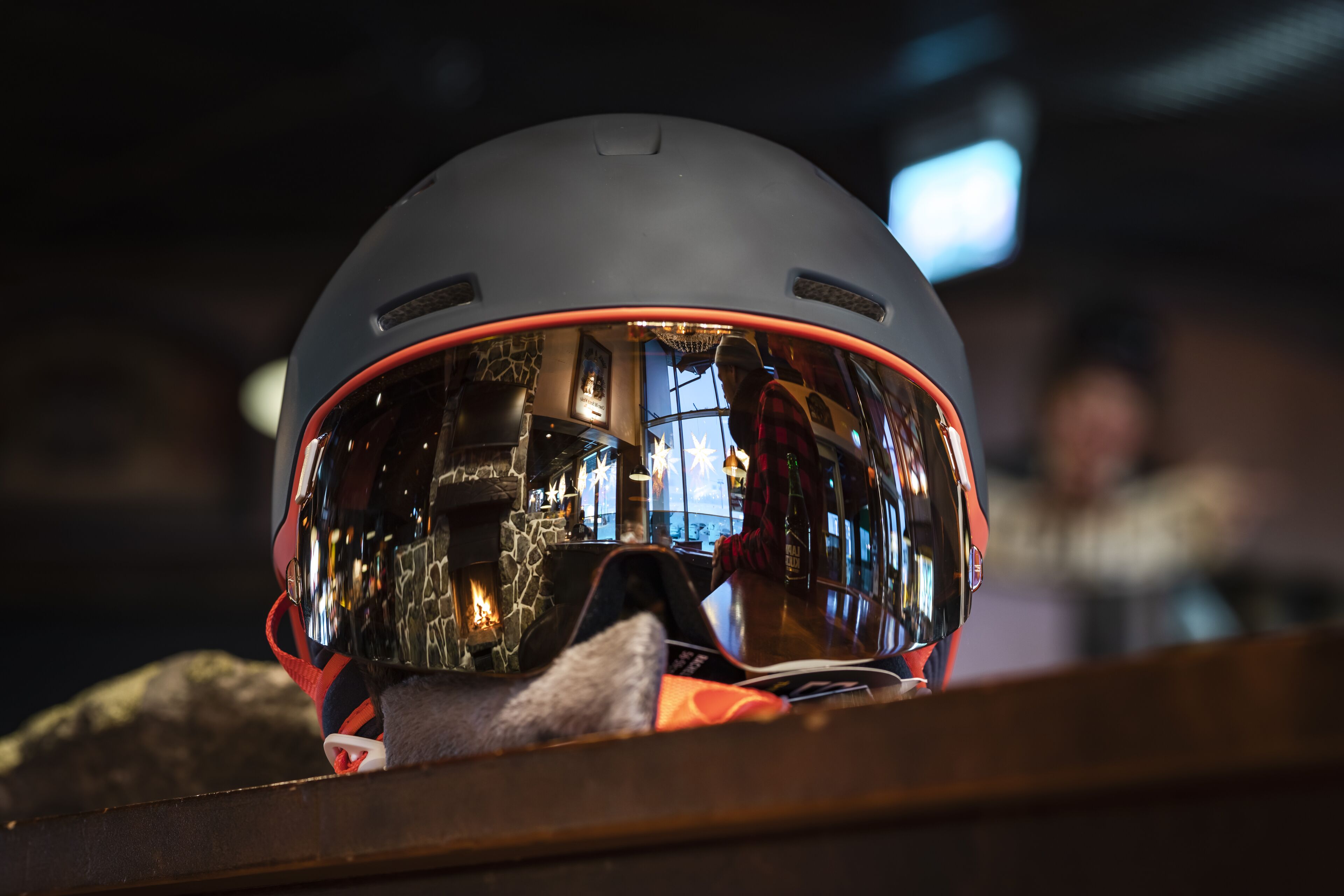 A helmet with a reflective visor, placed on a wooden surface.