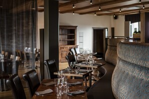 A restaurant with wooden tables and chairs, a bar area, and a seating section with patterned upholstery. - Lapland Hotels Saaga (Kolari)