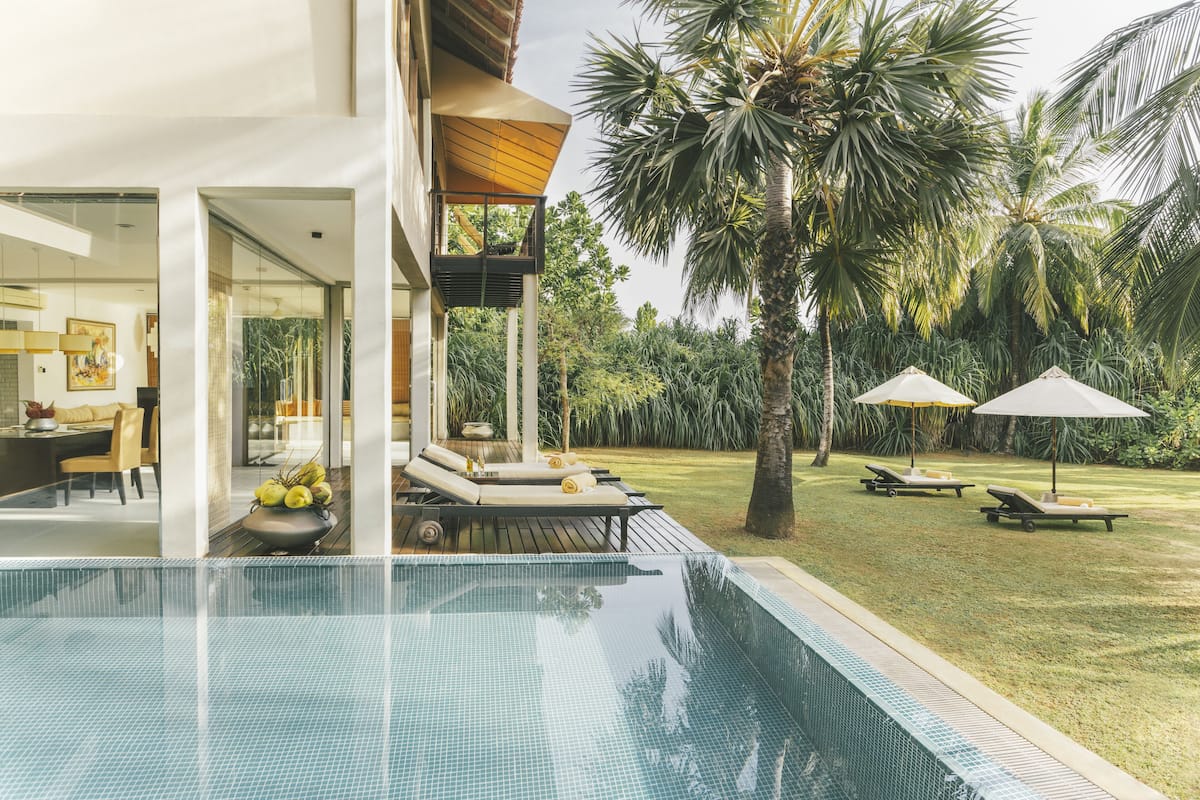 Un espace piscine moderne offrant une vue dégagée sur la piscine, des chaises longues et un coin repas.