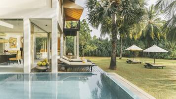 A modern pool area with a clear view of the pool, lounge chairs, and a dining area.