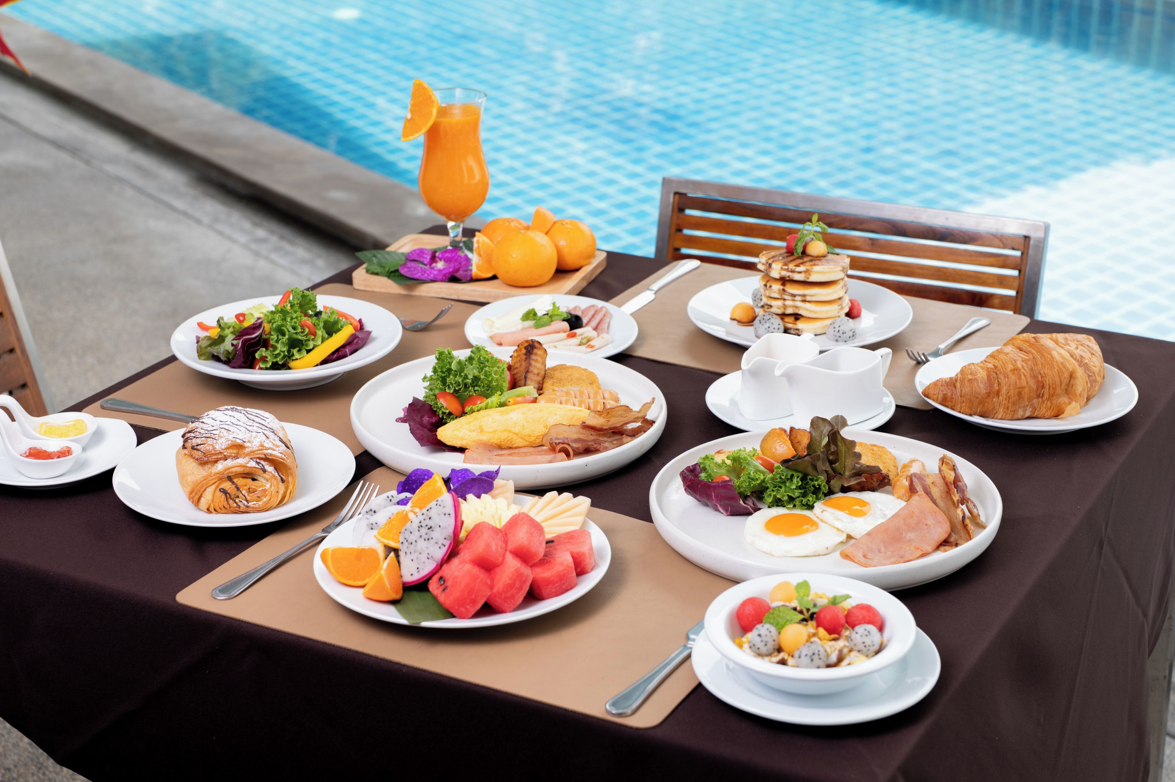 A table set with breakfast items including eggs, bacon, toast, and fruit.