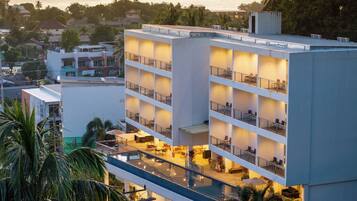 Un hotel de varios pisos con balcones, piscina y vista al océano.