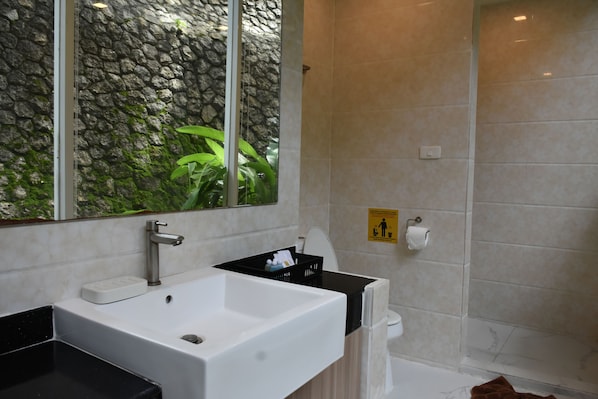 Ein modernes Badezimmer mit einem großen Waschbecken, einem Spiegel, einer Dusche und einer Steinwand.