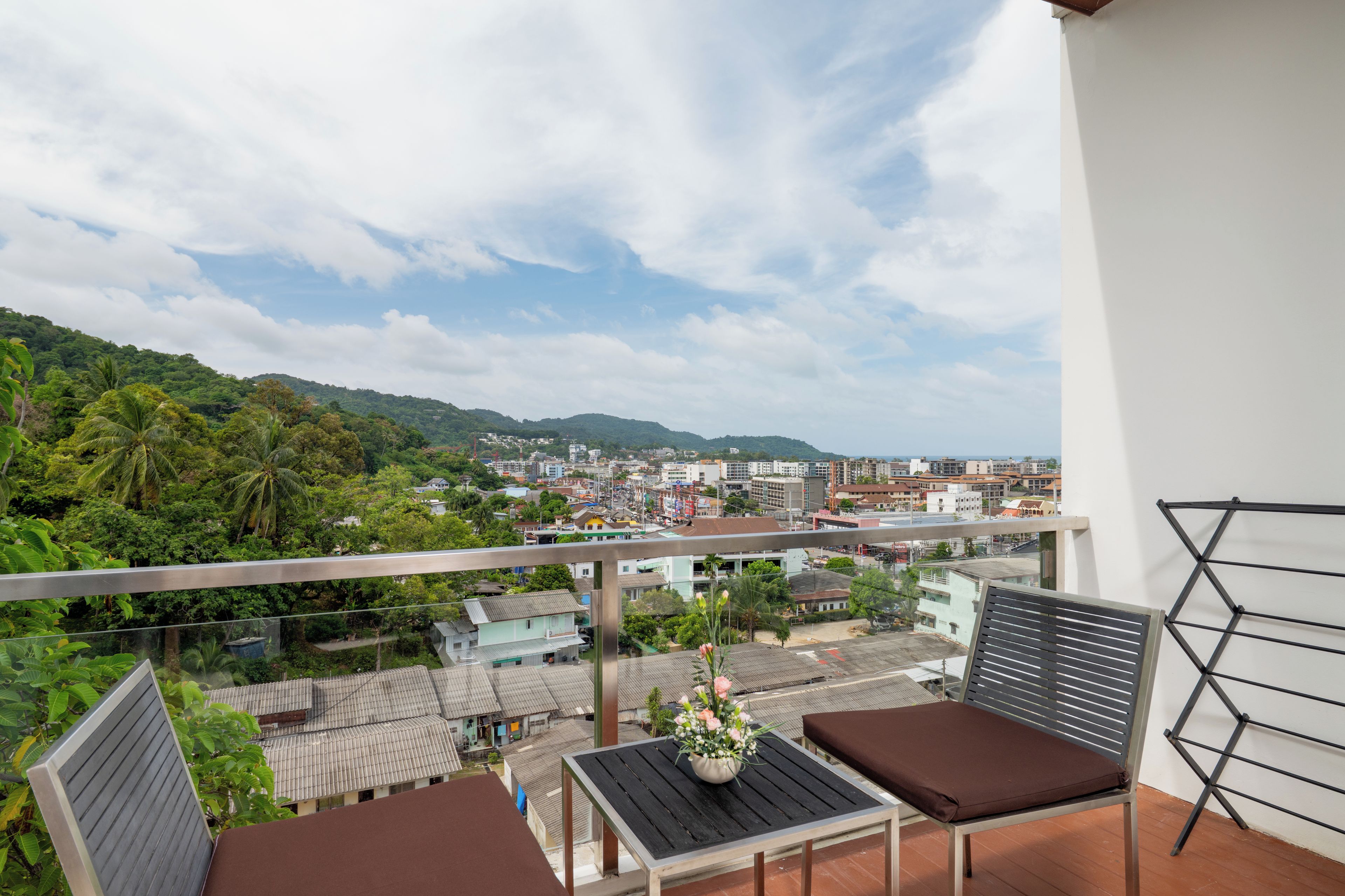 A balcony with a view of a cityscape and hills.