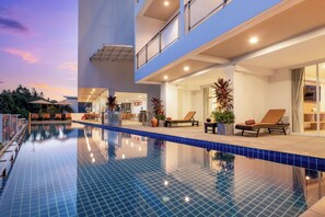 Ein modernes Hotel mit Swimmingpool, Liegestühlen und einem Restaurantbereich.