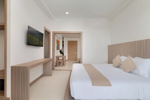 Une chambre d’hôtel avec un grand lit, un téléviseur fixé au mur et une tête de lit en bois.