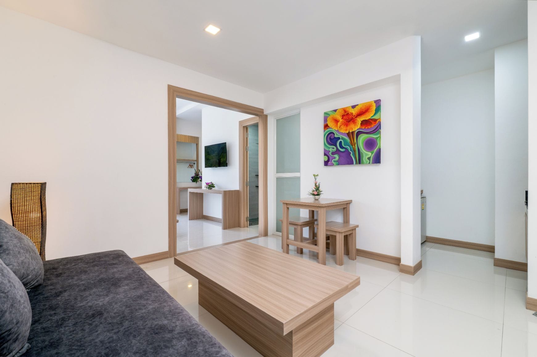 Una sala de estar moderna con un sofá, una mesa de centro y un televisor montado en la pared.
