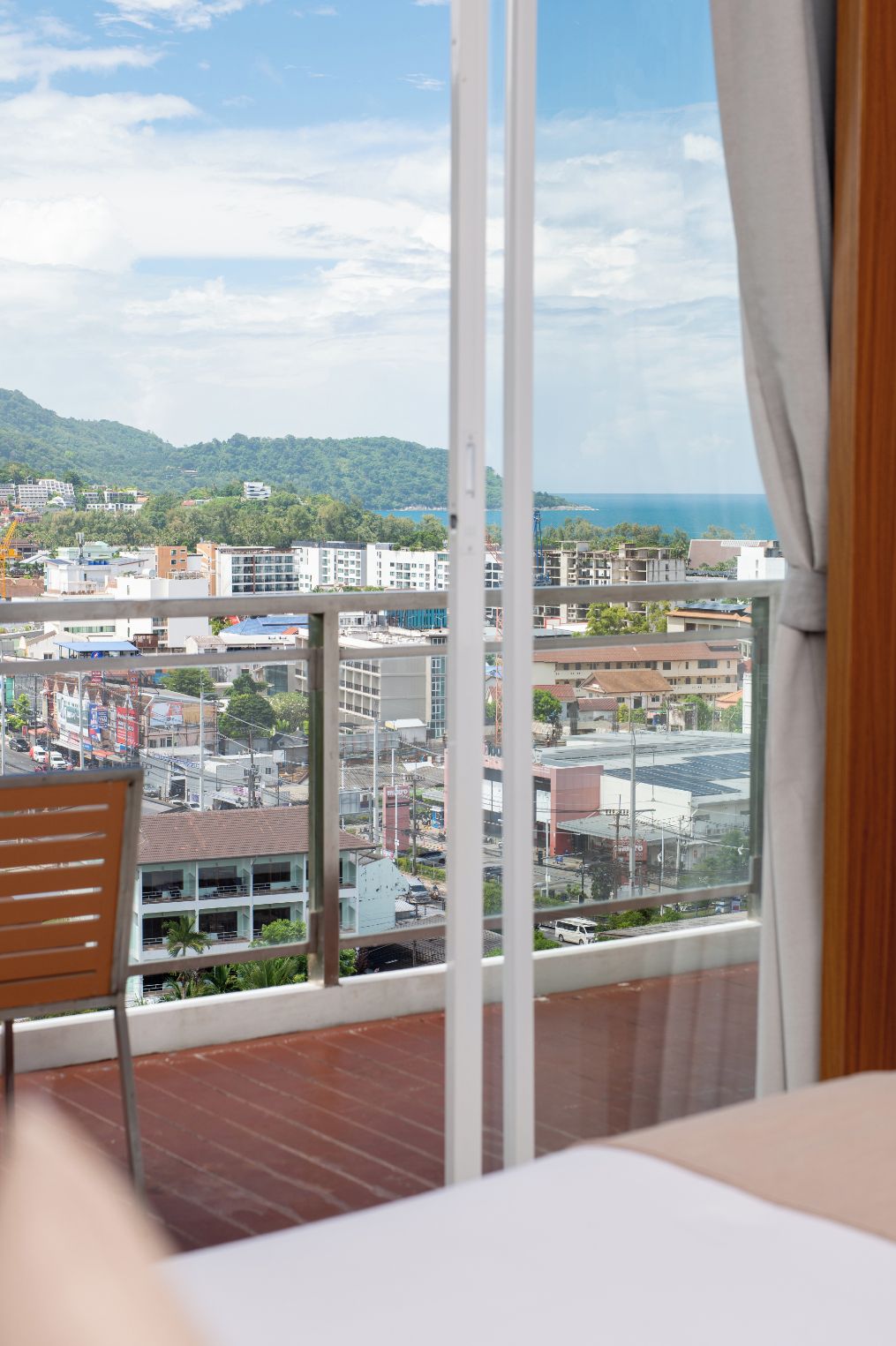 Habitación con un amplio ventanal que da a una vista urbana, piso de madera y una silla.