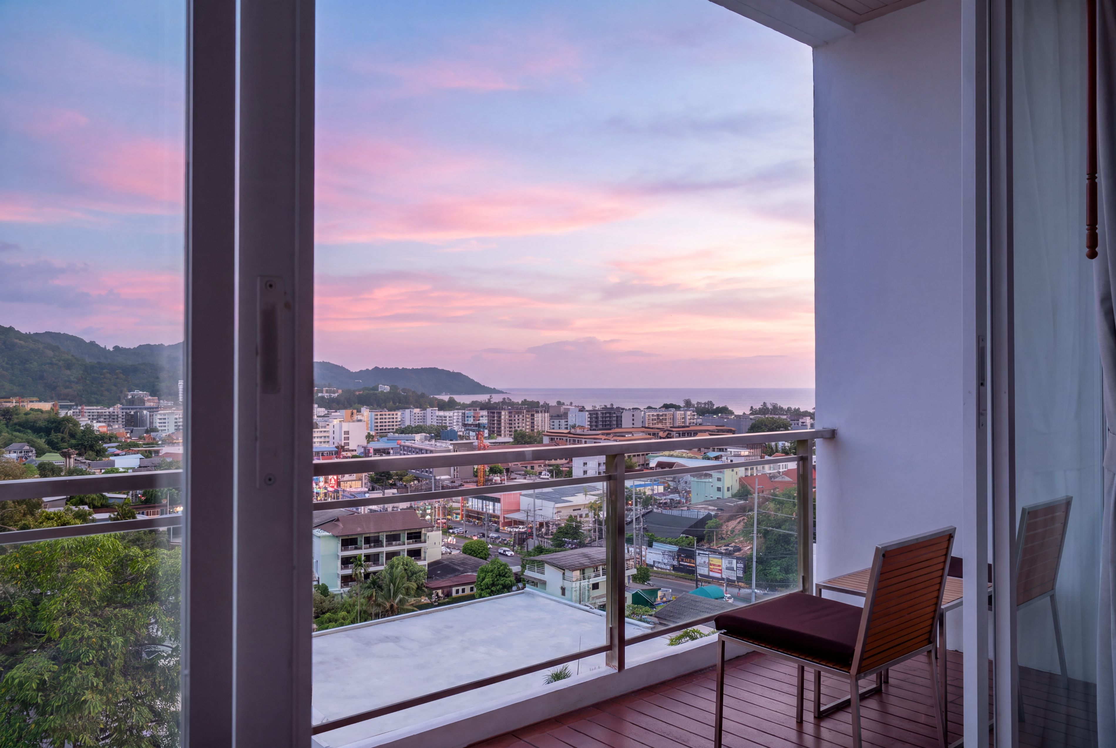 Un balcón con vista a un paisaje urbano y colinas al atardecer.