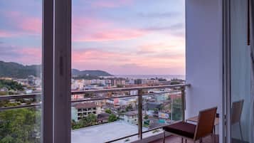 Un balcón con vista a un paisaje urbano y colinas al atardecer.