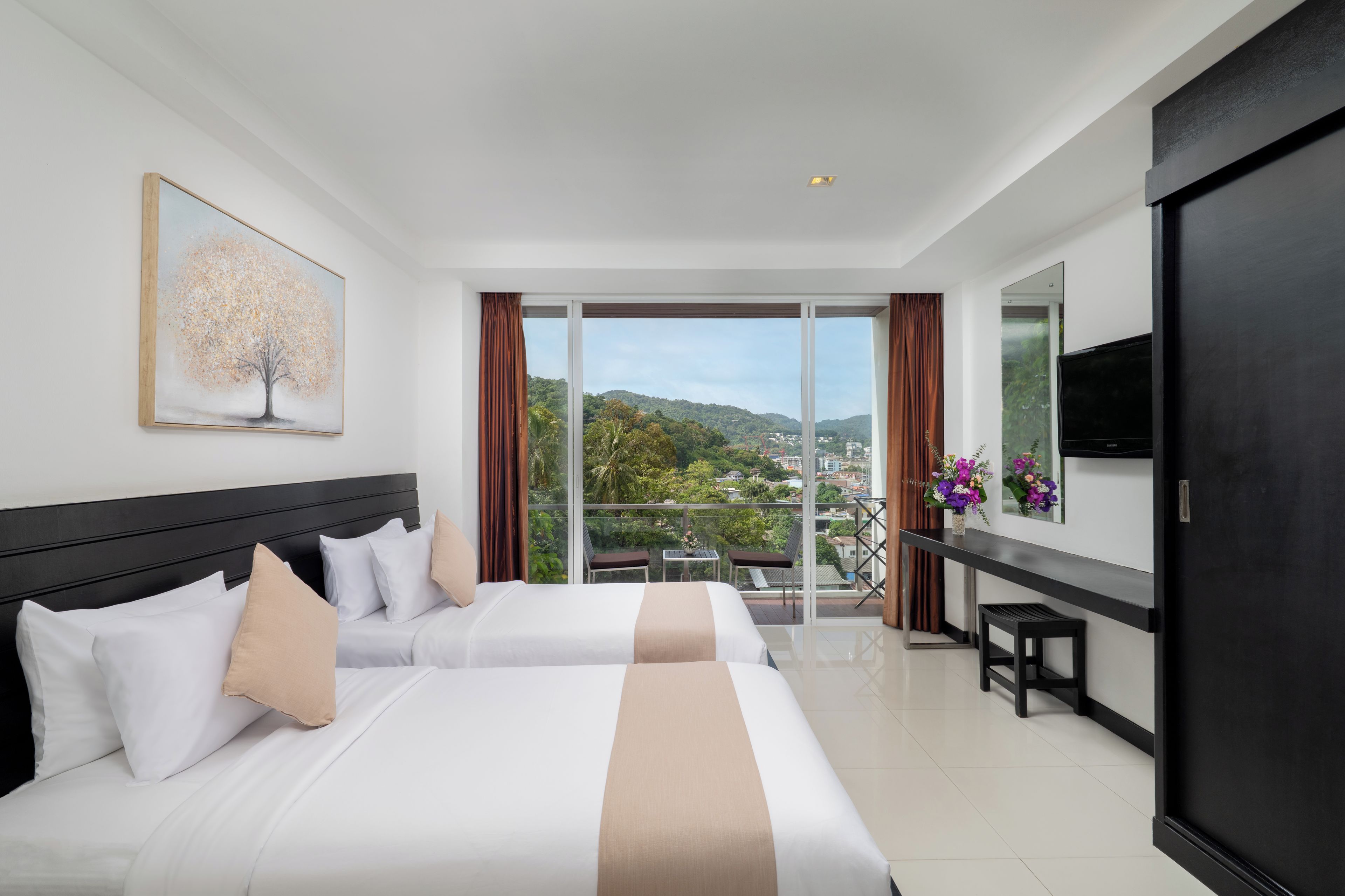 A hotel room with two beds, a large window with a view of the city, a flat-screen TV, and a desk with a chair.