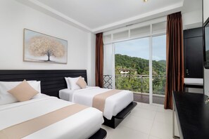 A hotel room with two beds, a large window with a view of greenery, and a flat-screen TV. - Laelay Suites (Karon)