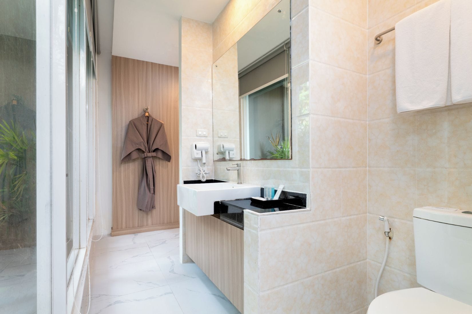 A modern bathroom with a large mirror, a sink, and a toilet.